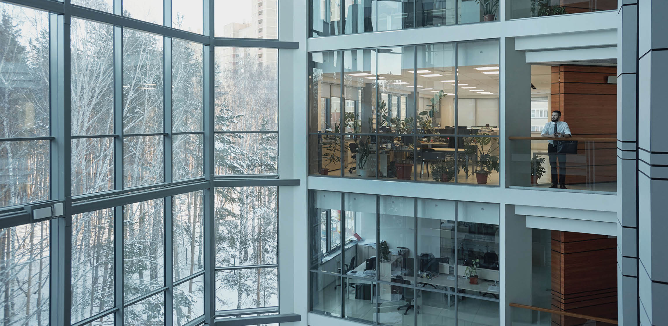 Interior of contemporary multi-floor business center with large windows and many offices in front of them