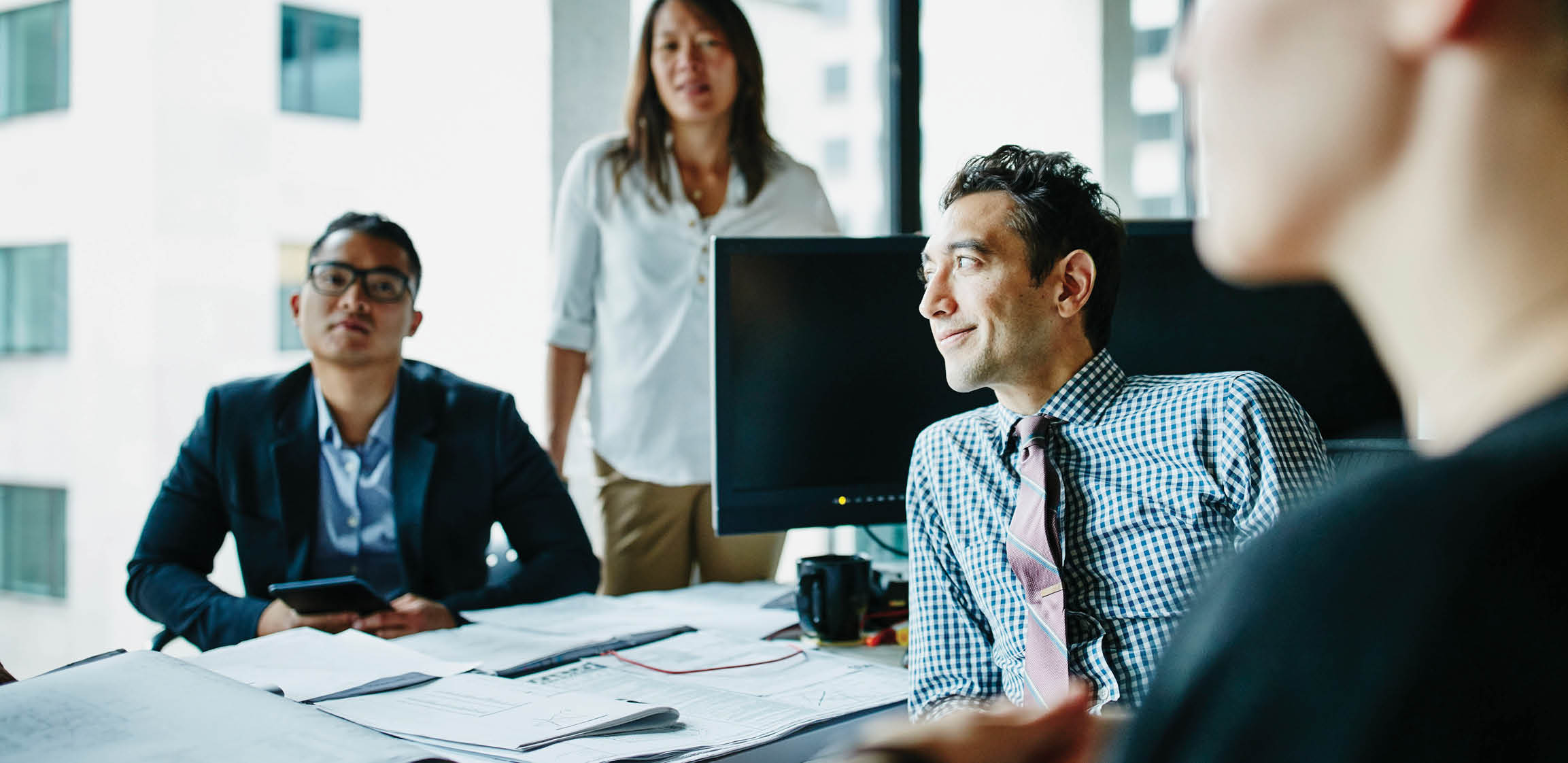 Smiling businessman leading team meeting at office workstation